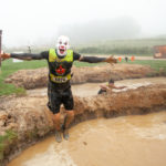 Participant with clown makeup jump in the mud