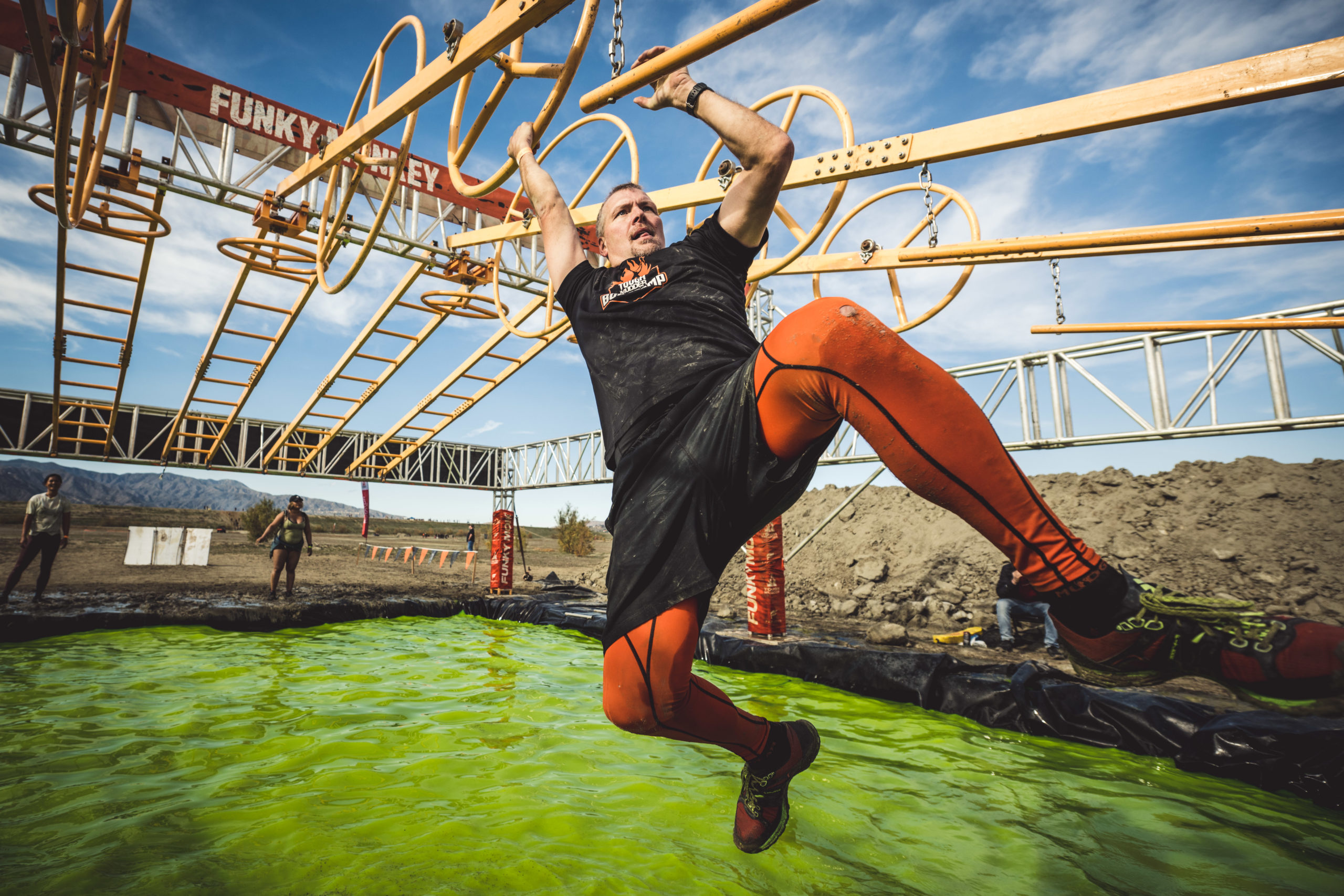 A man holding on the bars of Funky Monkey to avoid falling in the water