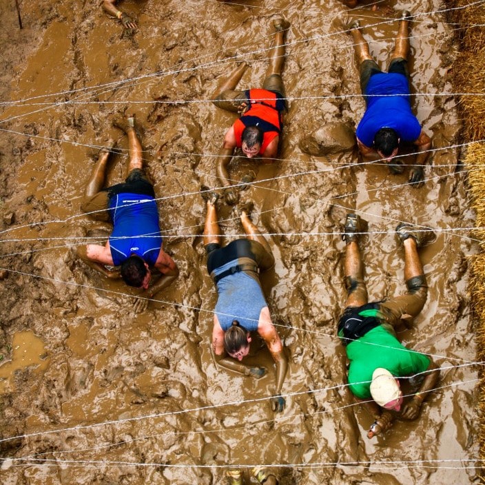 Mudders slowly crawling under the barbed wires of Kiss of Mud