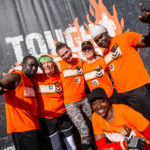Volunteers posing for a picture wearing thehir orange Tough Mudder shirt