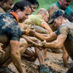 Participants helping their teammates pass through the mud