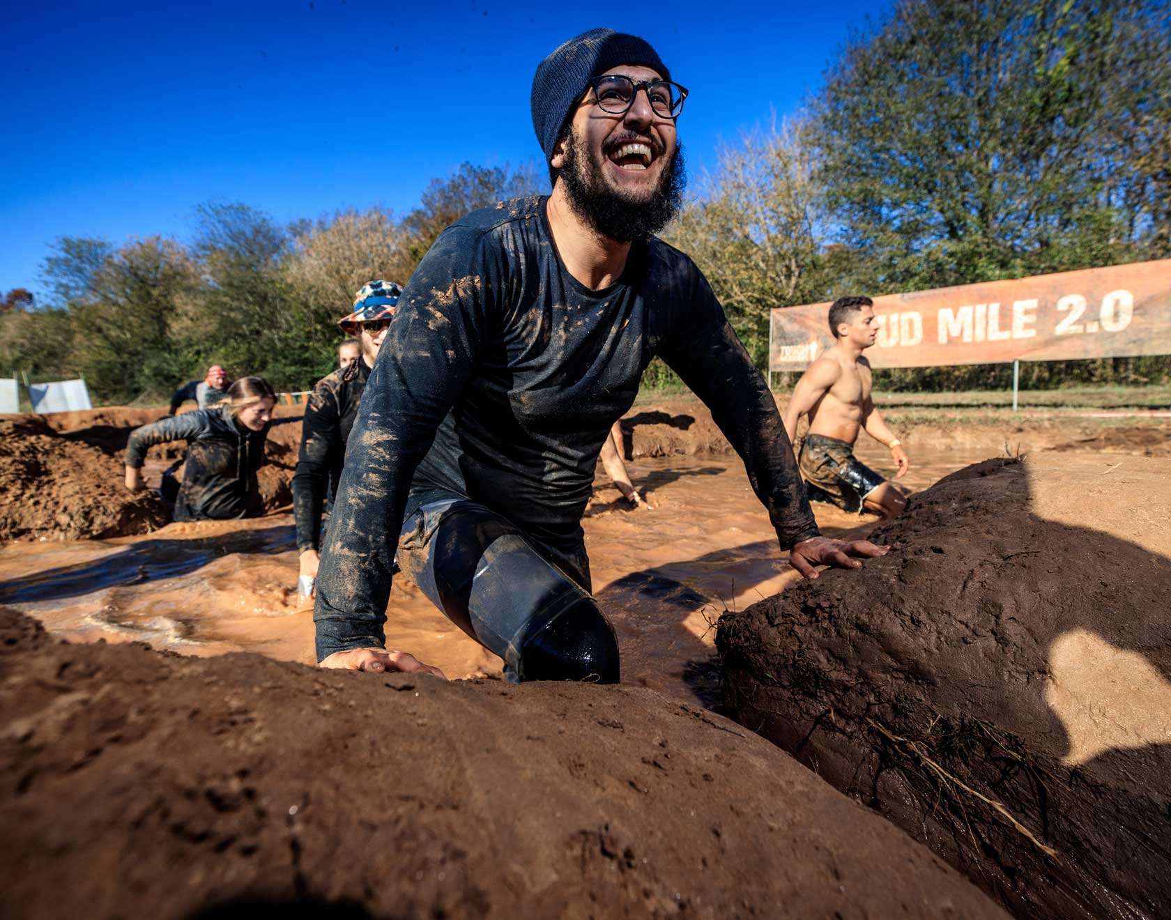 Participant smiling widely as he comes out of the mud