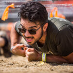 Man with beard participating in Kiss of Mud obstacle