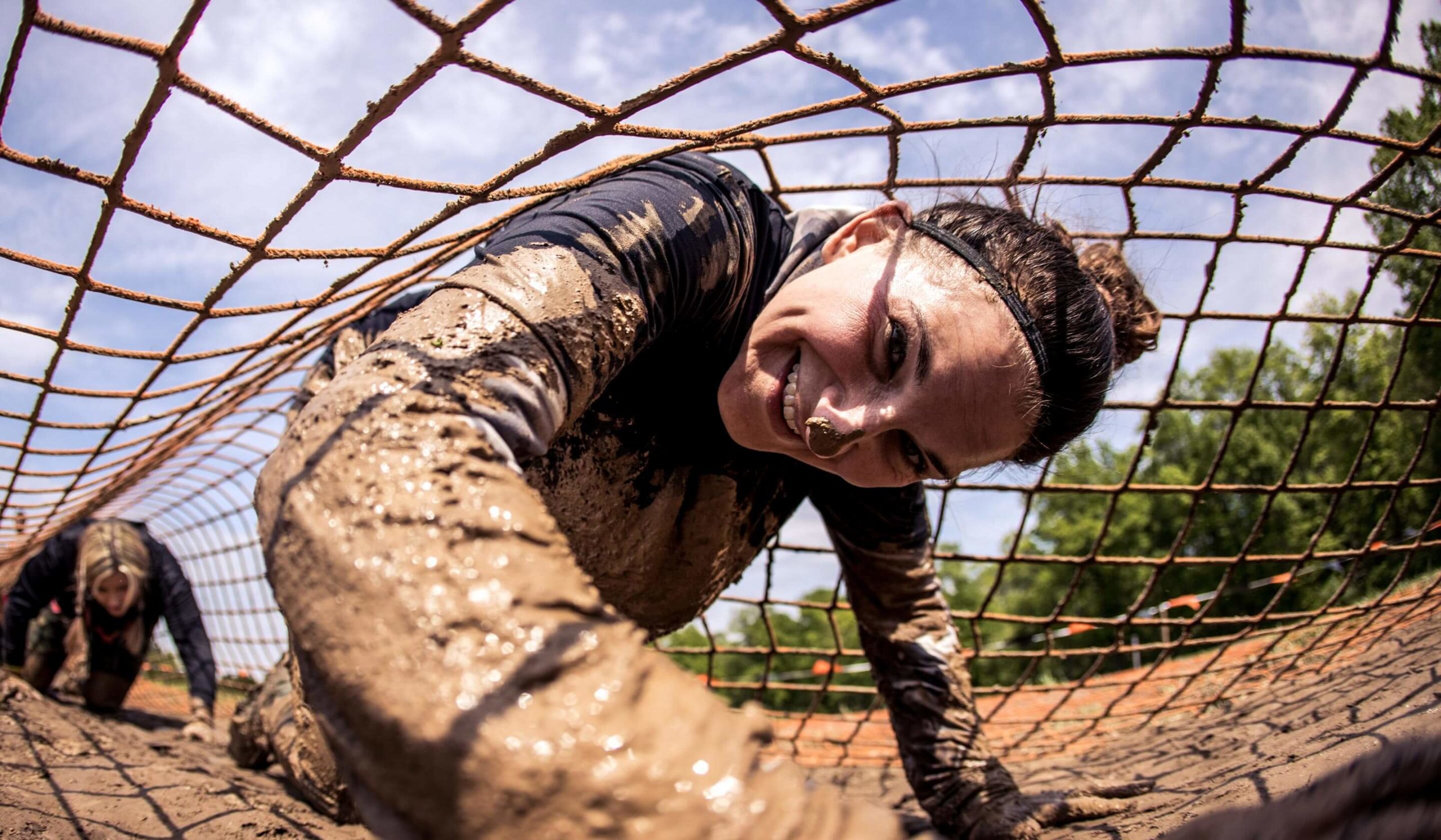 Smiling Devil's Beard participant covered in mud.
