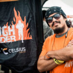 Participant crossed arms beside Tough Mudder flag