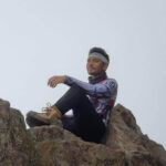 Participant sitting at the peak of a mountain