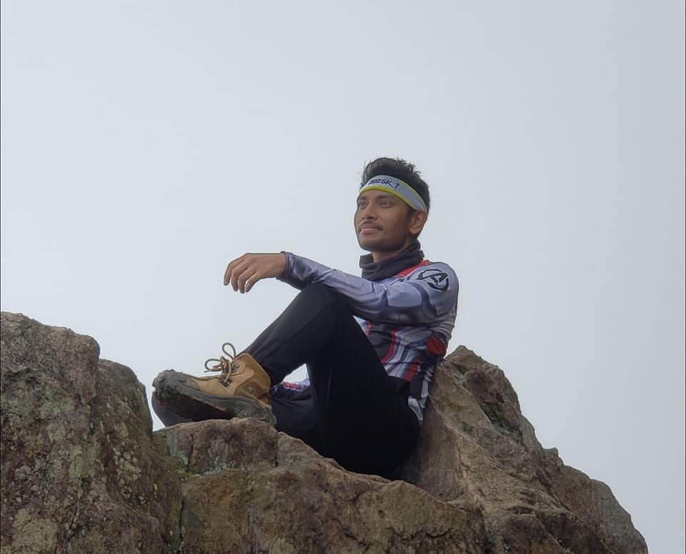 Participant sitting at the peak of a mountain