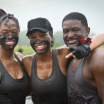 Three participants posing for a picture with mud in their faces