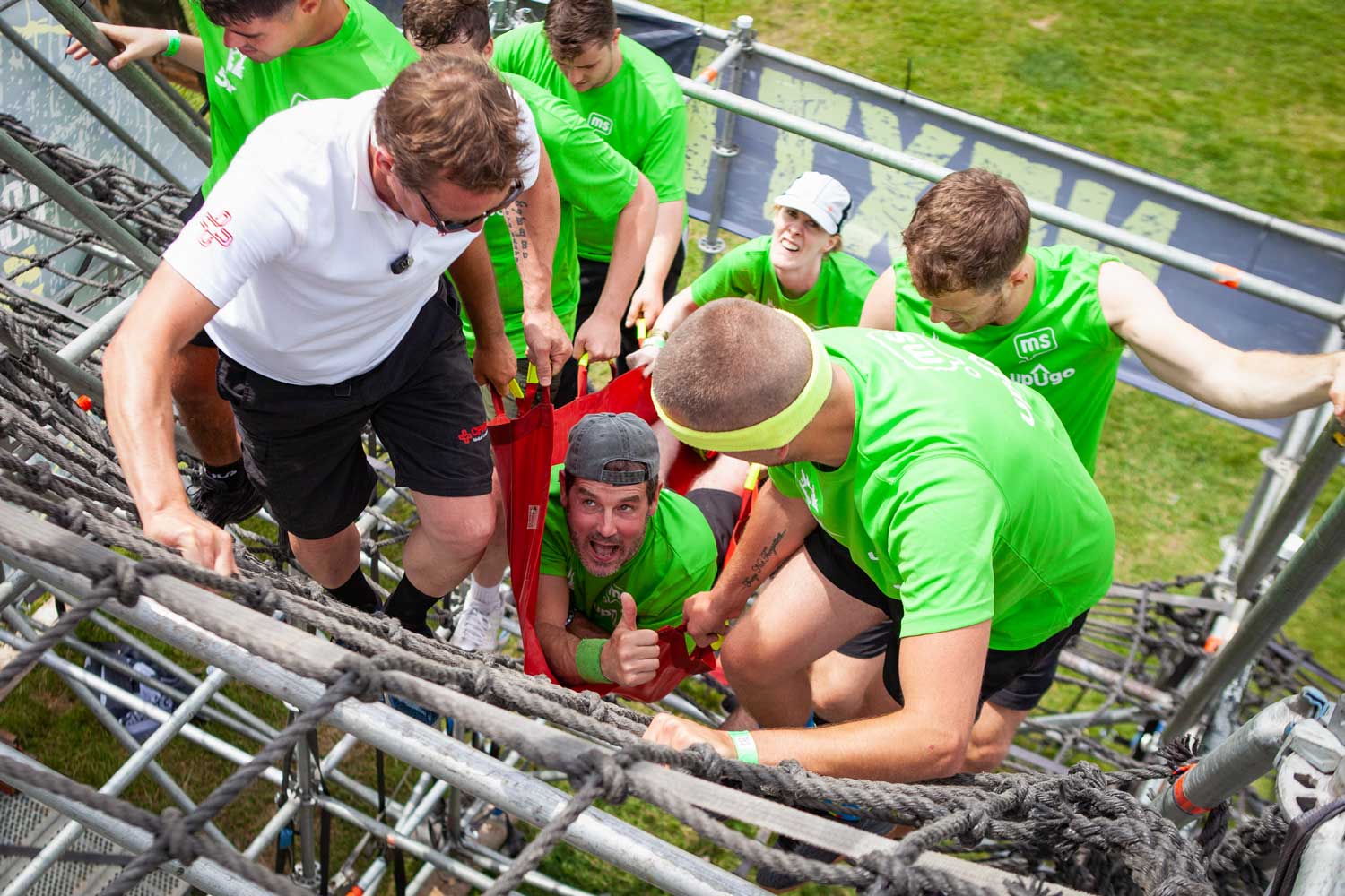 Teammates carrying their team member who has disability as they climb Mudderhorn