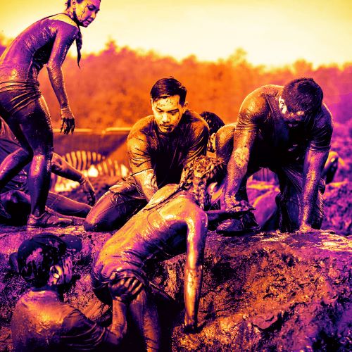 Participants helping their teammate to get up from the mud