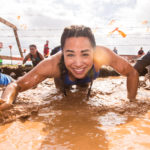 Participant smiling while crawling in the mud
