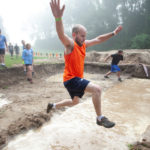 Participant in orange shirt jumped high to avoid the mud