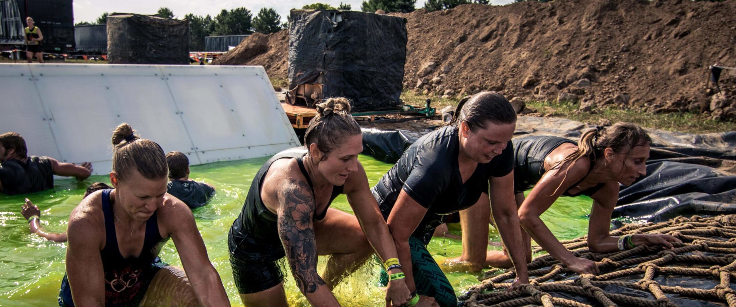 Four participants coming out of the waters to climb the rope