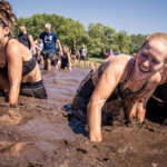 Participants laughing while crawling in the mud