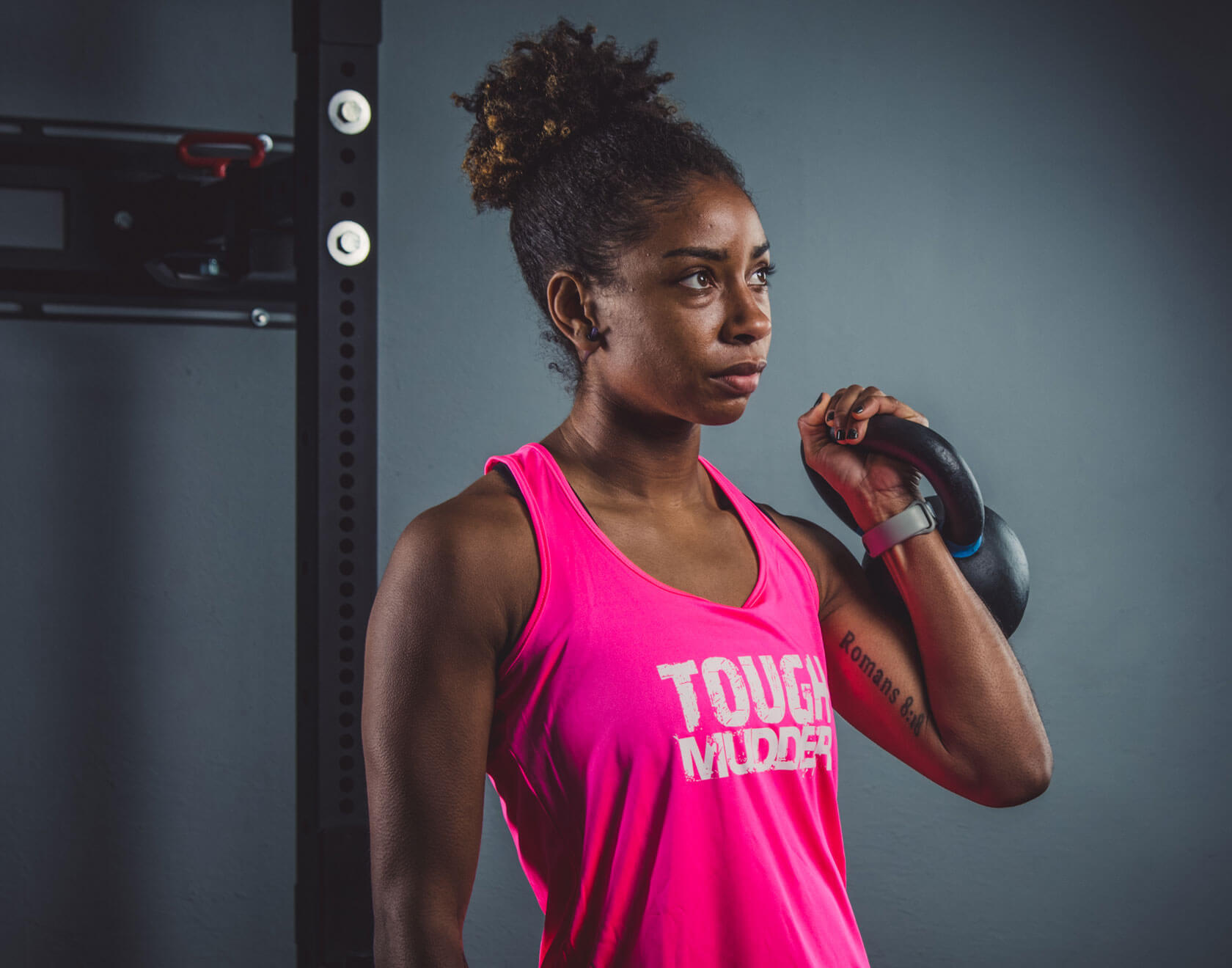 Woman in Tough Mudder shirt lifting kettle bell