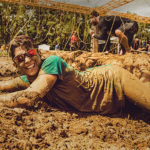 Participants smiling while crawling in the mud