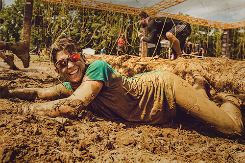 Participants smiling while crawling in the mud