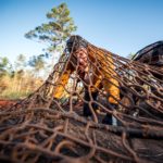 A participant crawling under the heavy net of Devil's Beard