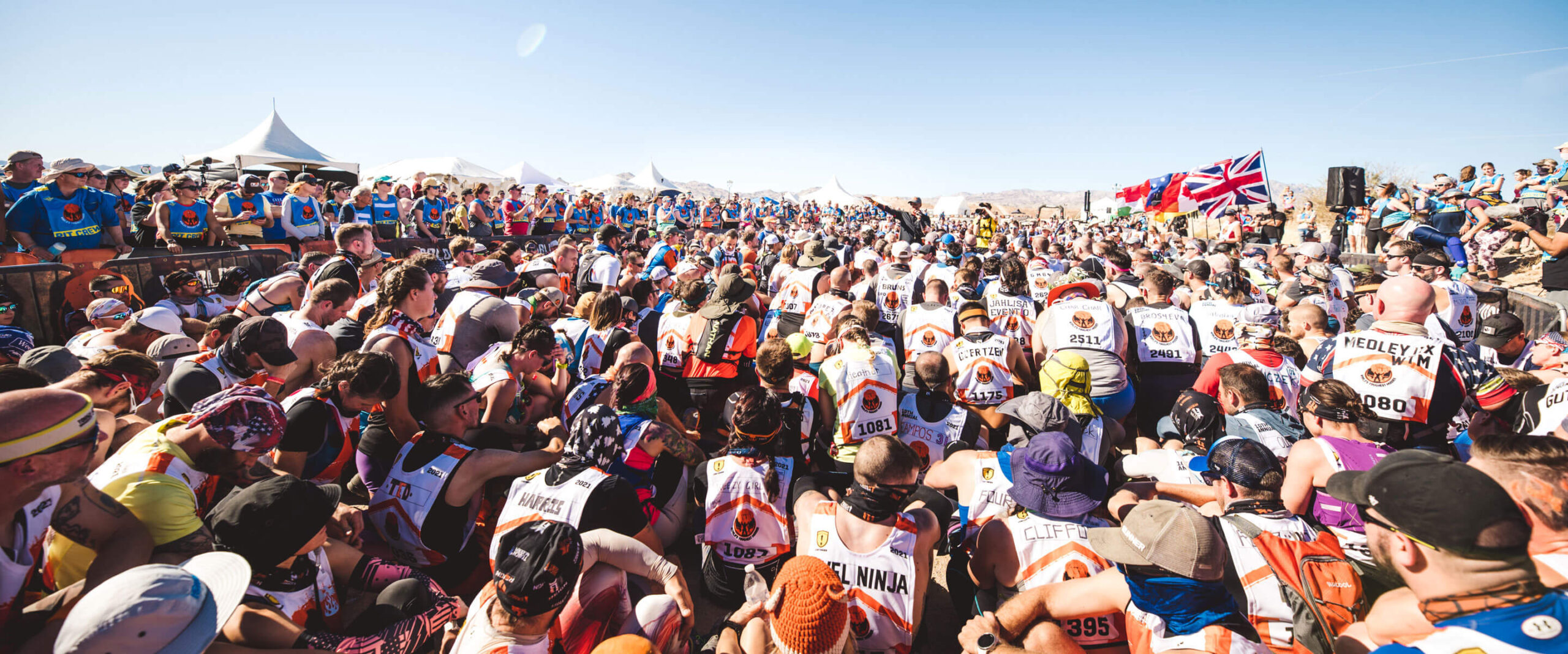 Mudders sitting while listening on announcement for Endurance mud course run