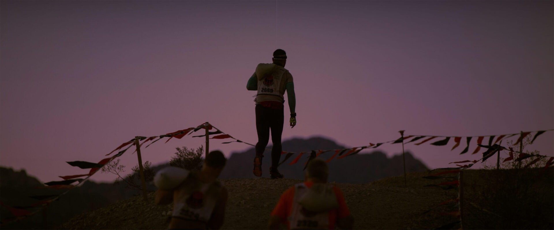 Mudders walking while holding a sack of sand