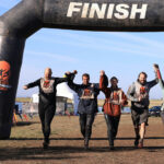 Mudders holding hands as they cross the finish line