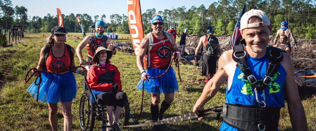 Mudders helping their teammate in a wheelchair