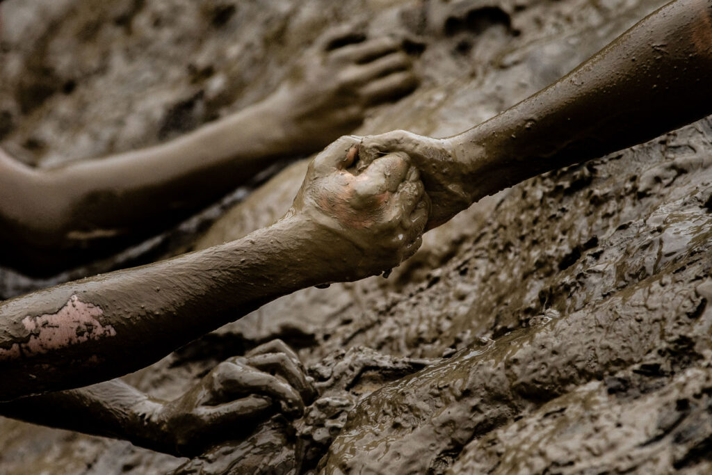 two muddy hands holding each other